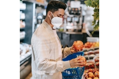 Image Person holding loose pomegranate in supermarket.
